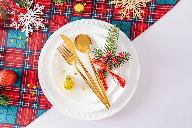 Bela vista do serviço festivo da mesa de Ano Novo ou Natal um conjunto de pratos brancos e talheres de ouro com decorações