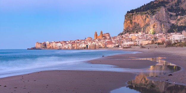 Bela vista panorâmica da praia e do centro histórico da cidade costeira de Cefalu durante a hora azul da noite, na Sicília, Itália