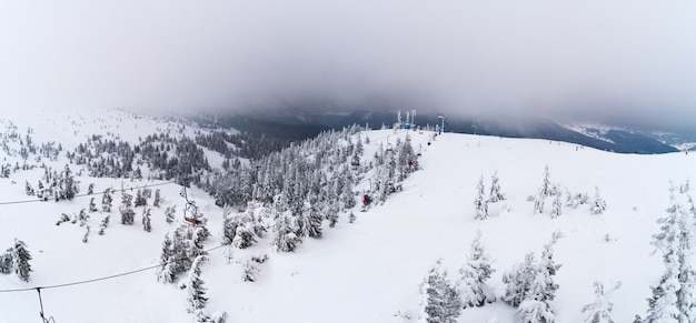 Bela vista panorâmica de um ponto alto na base de esqui com funiculares em um dia nublado de inverno