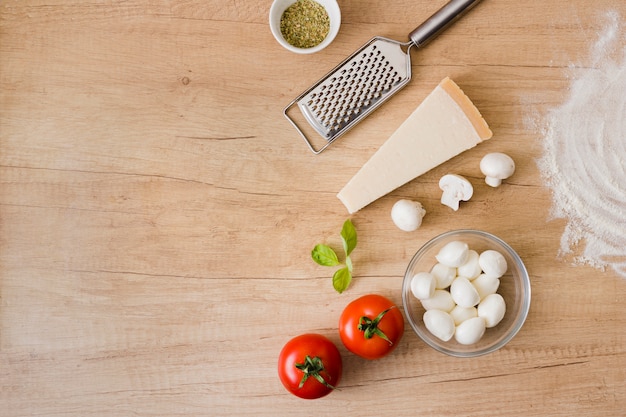 Belagbestandteile für Pizza mit Metallreibe auf hölzernem Hintergrund