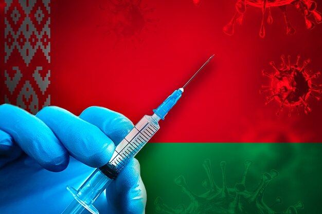 Belarus Covid19 Campanha de vacinação Mão em uma luva de borracha azul segura uma seringa na frente da bandeira