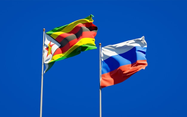 Belas bandeiras do estado nacional do Zimbábue e da Rússia juntos no céu azul. Arte 3D