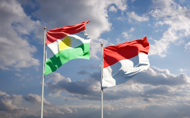 Foto belas bandeiras estaduais do curdistão e da indonésia juntas no céu azul