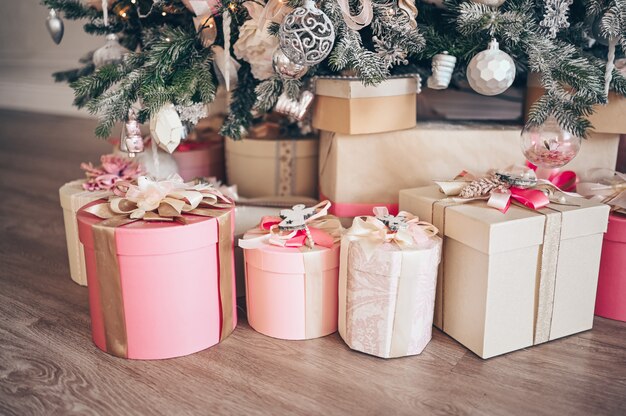 Belas caixas de presente de Natal no chão perto de abeto na sala