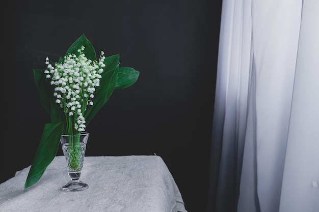 Belas Convallaria majalis em uma janela de mesa branca e fundo de parede preto