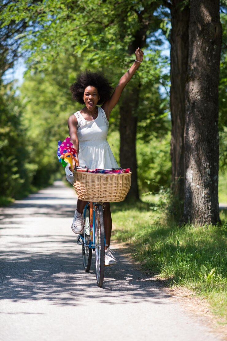 Foto belas jovens afro-americanas desfrutam enquanto andam de bicicleta na floresta em um dia ensolarado de verão