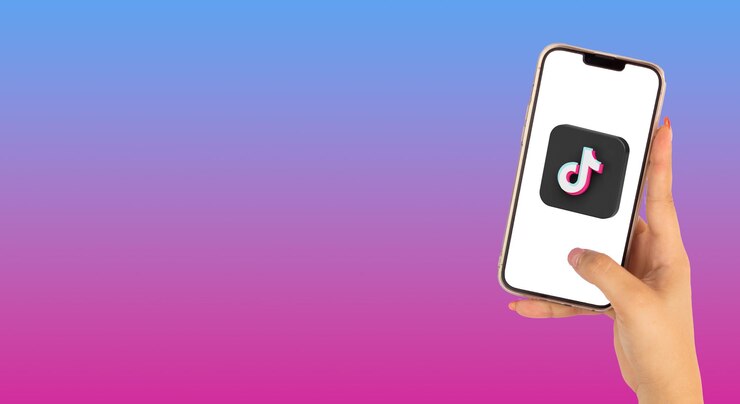 Foto belas mãos de uma mulher segurando o celular com o logotipo do tiktok