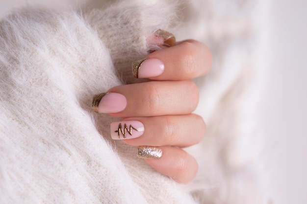 Belas mãos femininas com unhas de manicure bege e douradas em fundo branco