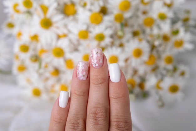 Belas mãos femininas com unhas de manicure rosa e branca desenho de flores