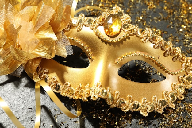 Belas máscaras de carnaval douradas e confetes em tabuleiro de textura cinza