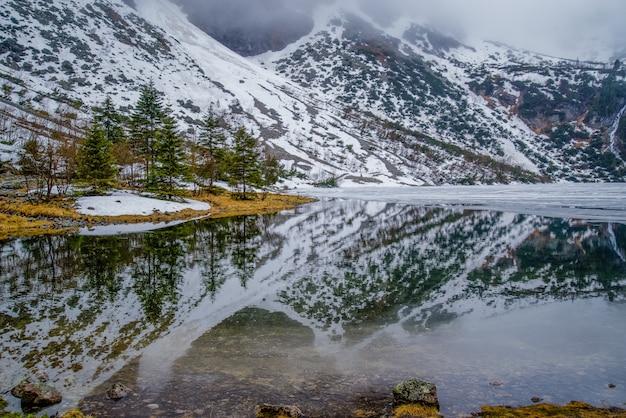 Belas montanhas cobertas de neve refletidas em um lago de montanha Morsko oko nas montanhas Tatra, Polônia