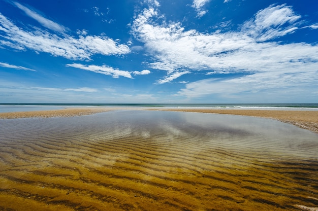 Foto belas nuvens brancas no céu azul sobre um mar calmo com reflexo da luz solar