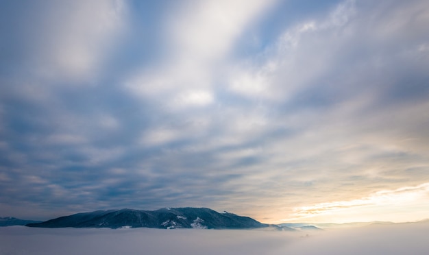 Belas paisagens mágicas dos picos das montanhas estão localizadas entre a neblina e as nuvens cirros