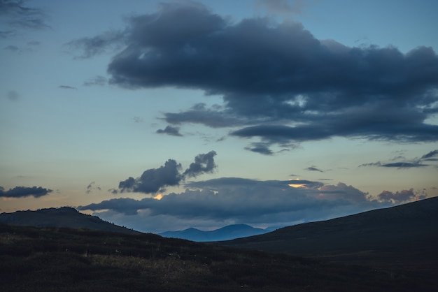 Belas paisagens montanhosas com luz dourada do amanhecer no céu nublado. Cênica paisagem montanhosa com cores iluminantes no céu do sol. Silhuetas de montanhas ao nascer do sol. Ouro iluminando a luz do sol no céu