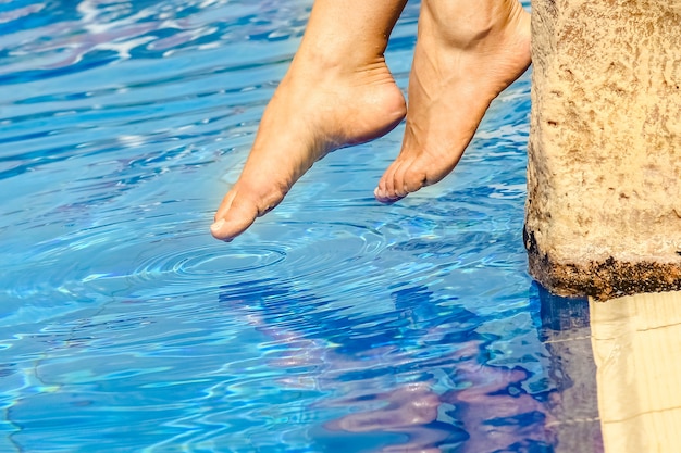 Belas pernas de uma garota perto de uma piscina na superfície do mar