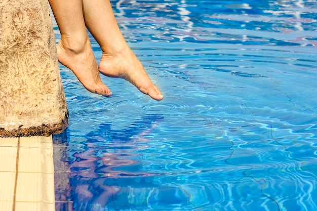 Belas pernas de uma garota perto de uma piscina na superfície do mar