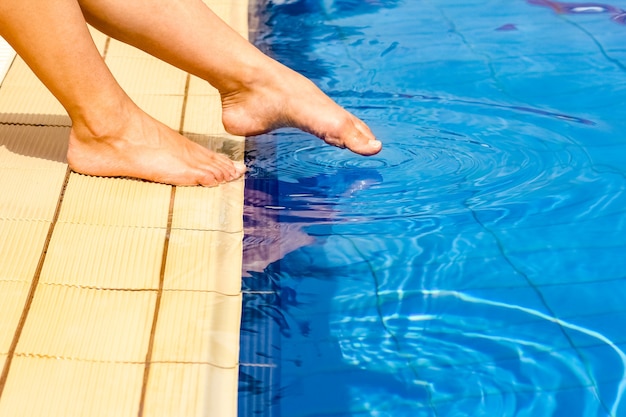 Belas pernas de uma garota perto de uma piscina na superfície do mar