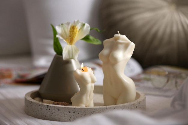 Belas velas em forma de corpo e flor na cama dentro de casa