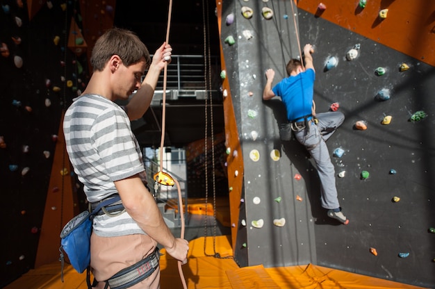 Belayer, der zuhause den Bergsteiger auf Felsenwand versichert