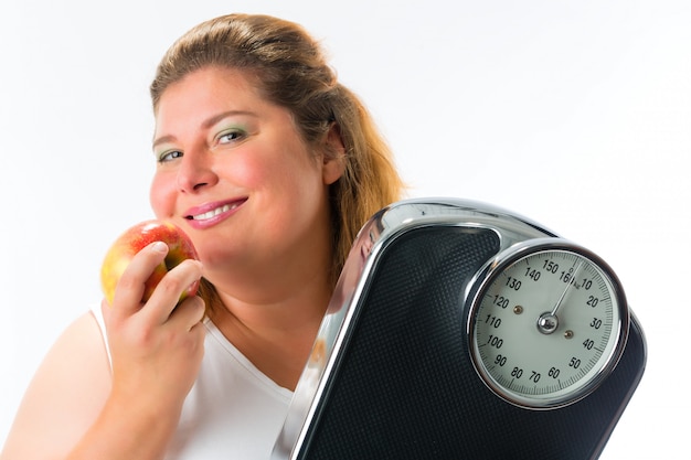 Beleibte Frau mit Skala unter Arm und Apfel