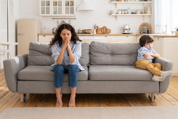 Beleidigte Mutter und Sohn sitzen auf der Couch im Wohnzimmer und vermeiden es zu reden