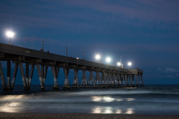 Foto beleuchtete brücke über dem meer gegen den himmel in der nacht