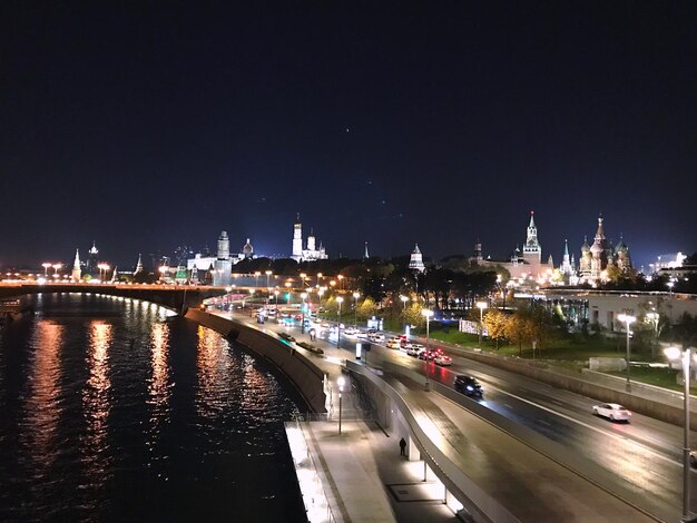 Beleuchtete Brücke über den Fluss von Gebäuden gegen den Himmel in der Nacht