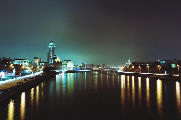 Beleuchtete Gebäude am Fluss gegen den Himmel in der Nacht