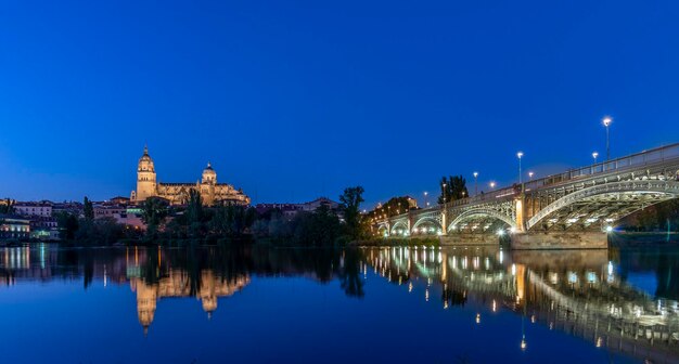 Foto beleuchtete gebäude am fluss gegen den klaren blauen himmel in der nacht