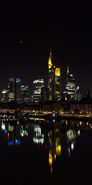 Foto beleuchtete gebäude am fluss gegen den nachthimmel