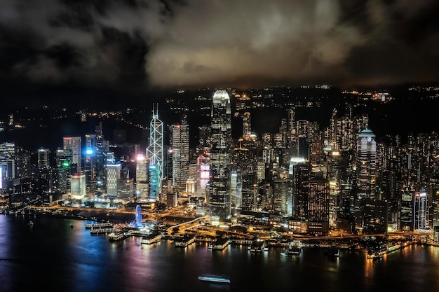 Beleuchtete Stadt am Meer gegen den bewölkten Himmel in der Nacht