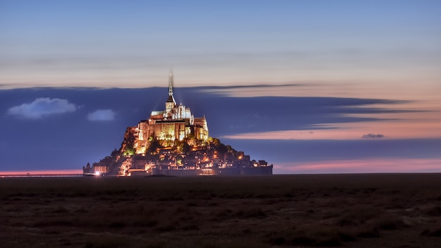 Beleuchteter Mont Saint Michel in der Abenddämmerung in einem bunten Himmel