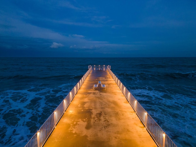 Beleuchteter Pier mit dramatischem Himmel über stürmischer dunkler See am Abend Varna Bulgarien