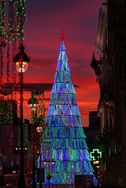 Beleuchteter Weihnachtsbaum, der in der Dämmerung in der Mitte des Platzes Puerta del Sol in Madrid steigt.