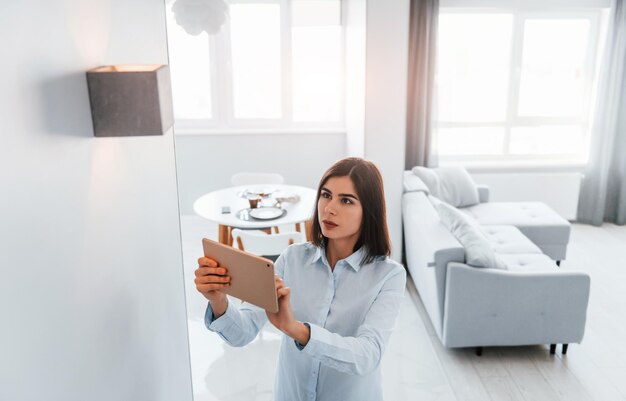 Beleuchtung umschalten Junge Frau ist tagsüber im Zimmer des Smart House