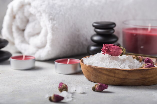 Beleza ainda vida de garrafa de óleo de massagem de sal de aroma essencial e natural de fragrância com pedras, velas na mesa de concreta cinza. Composição do tratamento de spa