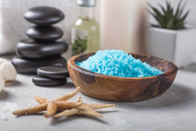 Beleza ainda vida de garrafa de óleo de massagem de sal de aroma essencial e natural de fragrância com pedras, velas na mesa de concreta cinza. Composição do tratamento de spa