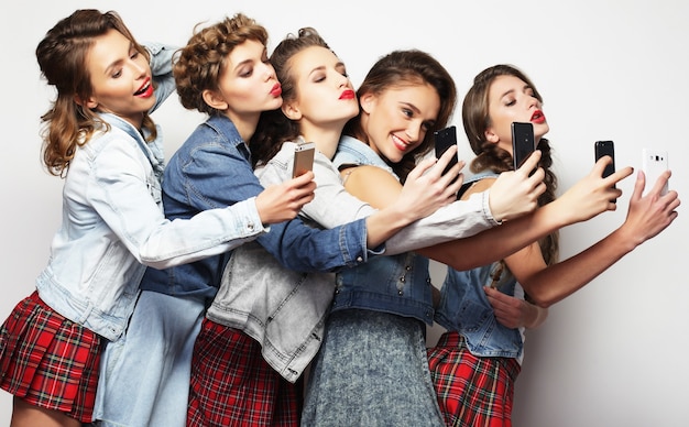 Beleza, amizade, juventude e tecnologia. Retrato de estúdio de cinco lindas mulheres jovens tomando selfie.