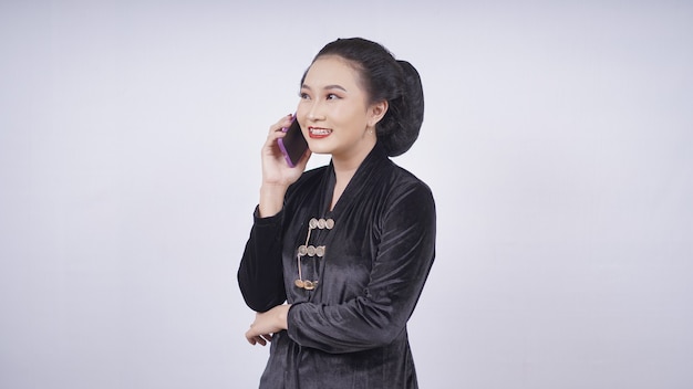Beleza asiática em kebaya está no telefone, isolada no fundo branco