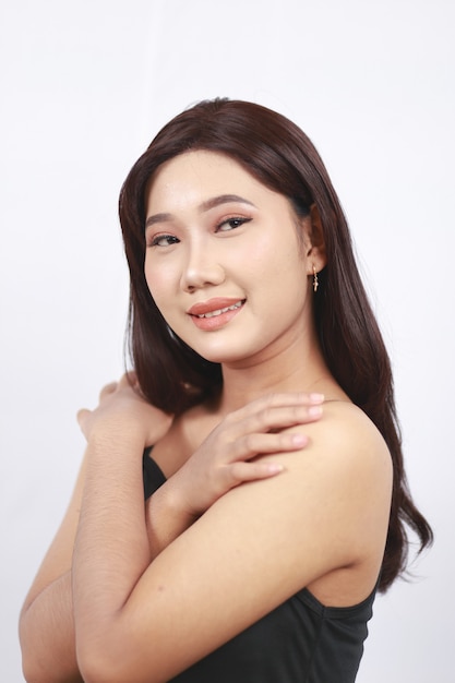 Beleza asiática sorrindo com a mão no ombro, isolada no fundo branco