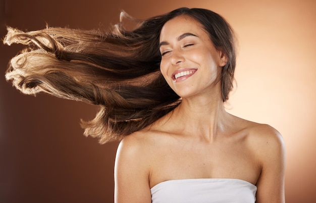 Beleza capilar e cuidados com a pele com uma mulher modelo em estúdio em um fundo marrom para tratamento natural ou com queratina Cuidados com os cabelos e salão de beleza com uma mulher jovem e atraente posando para promover um produto