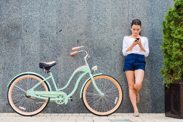 Beleza com bicicleta vintage. Mulher jovem e bonita sorridente em pé perto de sua bicicleta vintage na rua