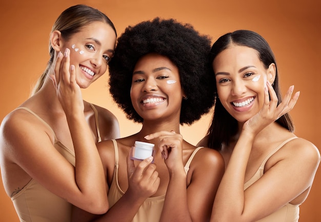 Foto beleza creme para o rosto cuidados com a pele e mulheres retrato hidratante estética saudável e pele brilhante em fundo de estúdio laranja grupo de amigos de diversidade feliz produto facial maquiagem cosméticos e bem-estar