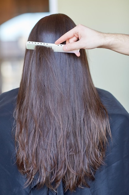 beleza, cuidados com os cabelos, penteado e conceito de pessoas - mão de estilista com pente penteando o cabelo da mulher no salão