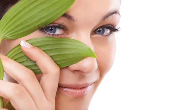 Beleza da maneira natural Retrato aproximado de uma mulher olhando para a câmera através de folhas verdes