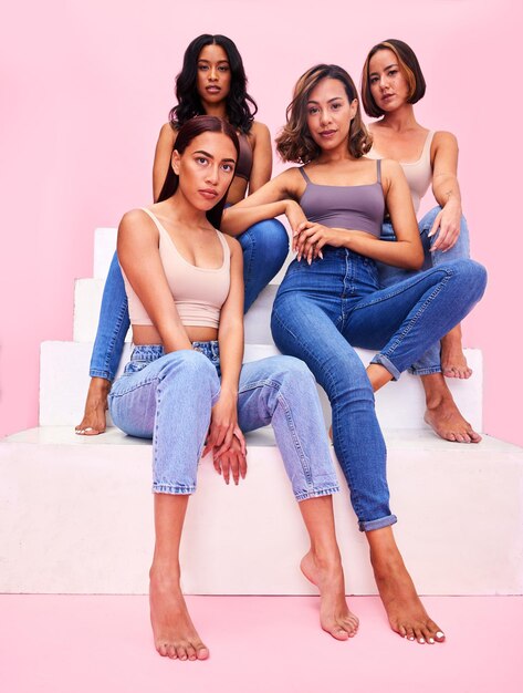 Foto beleza da moda e retrato de mulheres nas escadas em estúdio para desconto de promoção de roupas e venda no varejo amigos beleza e pessoas em fundo rosa em roupa jeans estilo moderno e casual