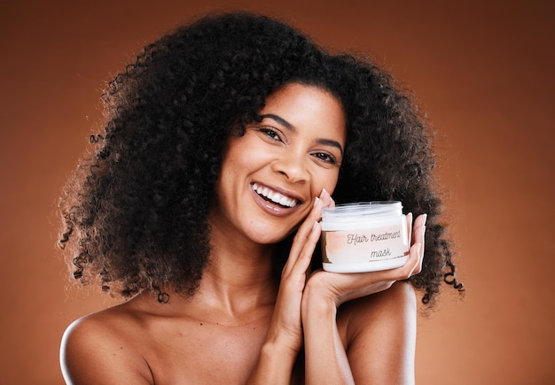 Foto beleza de cabelo e mulher negra com tratamento para saúde estética de retrato e bem-estar em um fundo de estúdio marrom creme de penteado e hidratante com uma mulher afro-americana para cosméticos