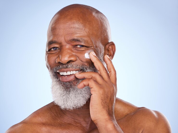 Foto beleza de cuidados com a pele e retrato de homem negro e creme em estúdio para protetor solar antienvelhecimento ou spa maquete de cosméticos ou autocuidado com loção no rosto de modelo em fundo azul para rosto e produto