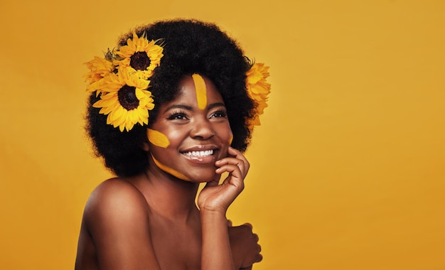 Beleza de girassol e mulher negra feliz em estúdio para maquiagem, bem-estar e tratamento em fundo amarelo Cuidados com a pele de flores e sorriso de modelo feminino africano relaxam e posam com cosméticos naturais para a pele