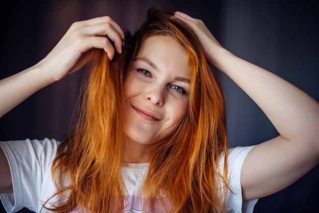 Beleza de olhos verdes toca o cabelo e olhando para a câmera e sorrindo. Publicidade de cuidados, coloração de cabelo